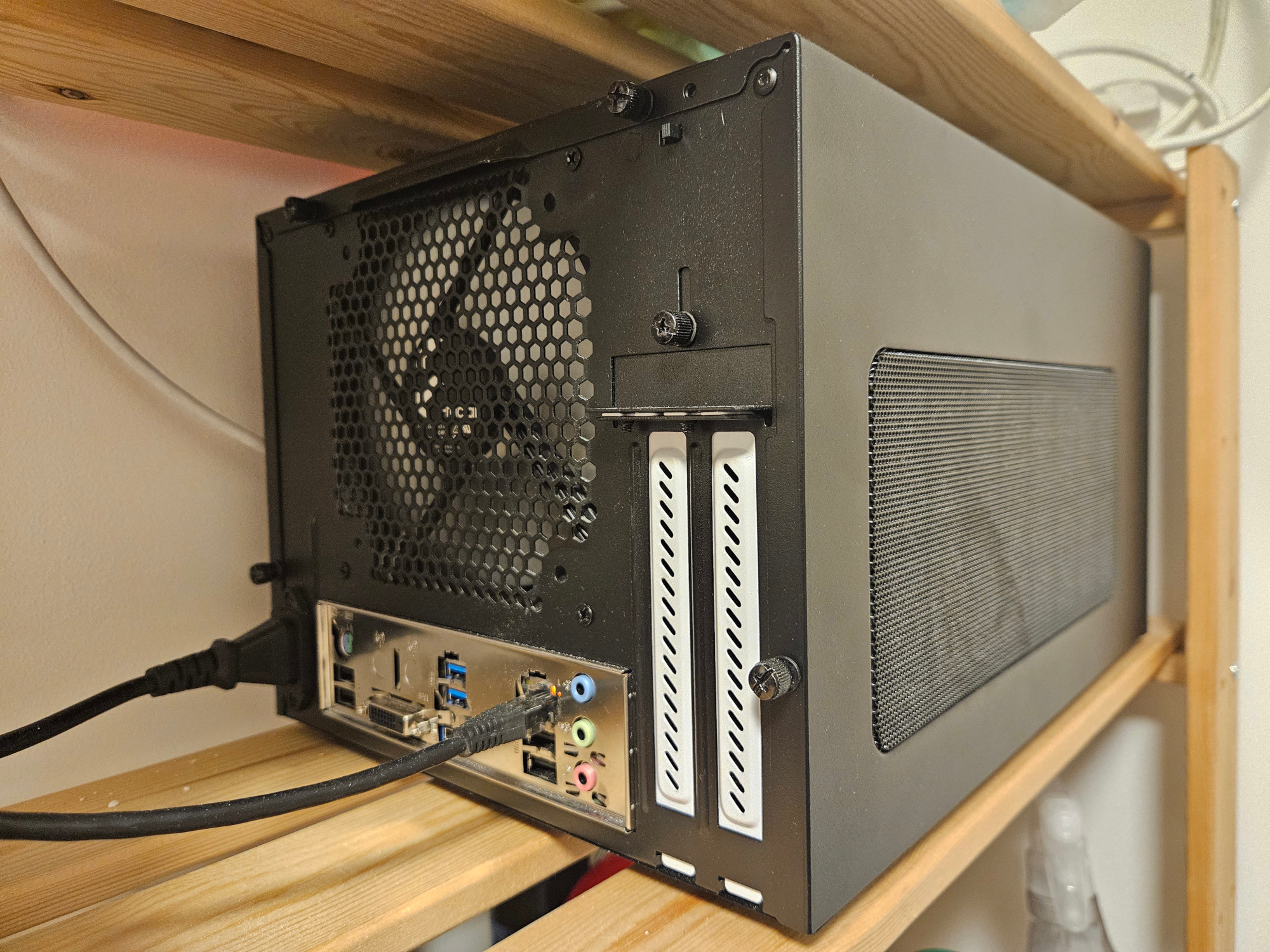 Fotografie zadní části NAS serveru s velkým ventilátorem a konektory základní desky.